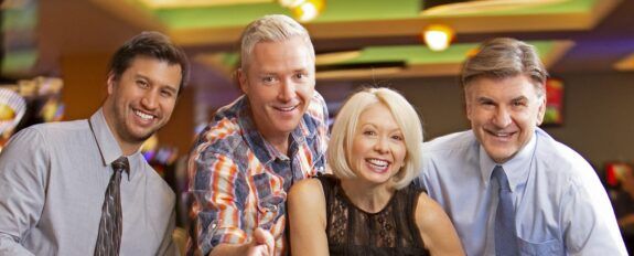 Three men and a woman gamble at a table at The Lodge Casino.