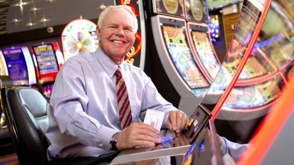 A man in a suit plays a slot machine at The Lodge Casino.