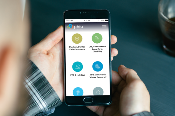 A person with a smartphone looks at icons for employee benefits on the phia website.
